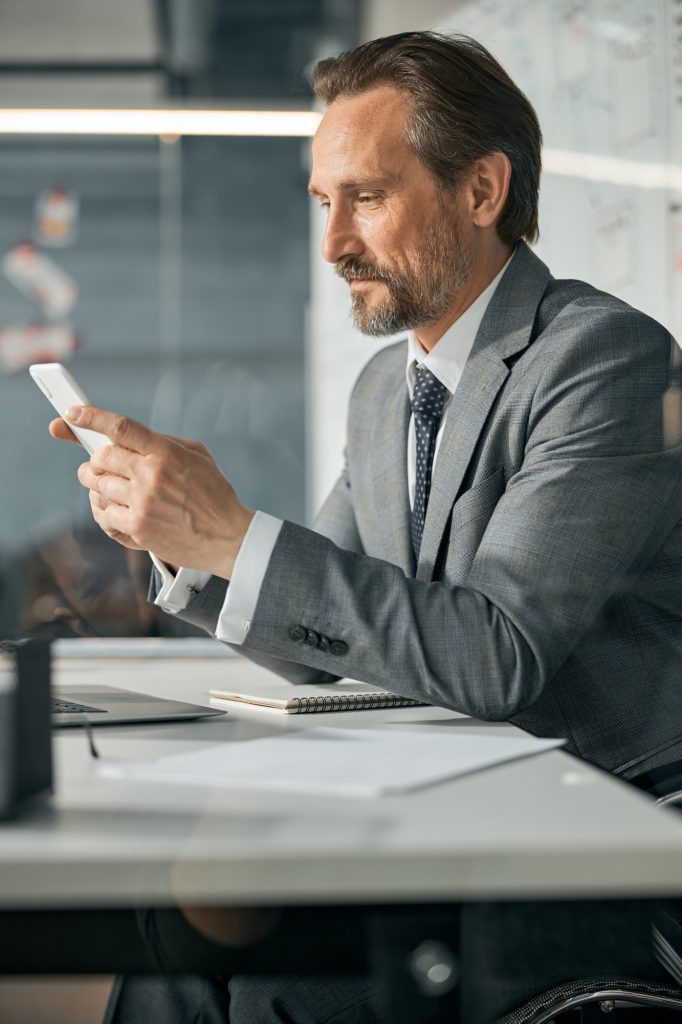 Caucasian male is using phone at the desk